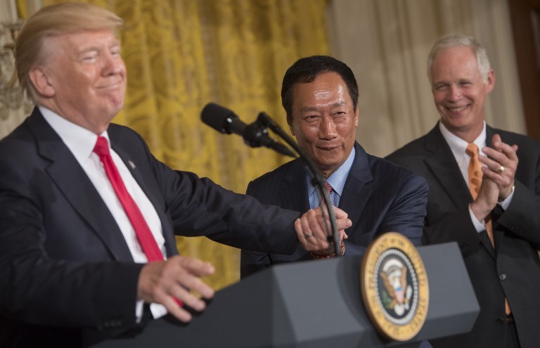 ADJUSTED PLANS? US President Donald Trump shakes hands with Terry Gou (C), Chairman of Foxconn, an electronics supplier, during an announcement that the company will open a manufacturing facility in Wisconsin, during an event in the East Room of the White House in Washington, DC, July 26, 2017. File photo by Saul Loeb/AFP 