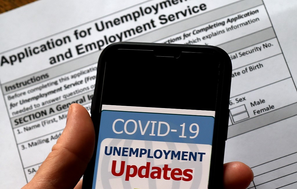 JOBLESS CLAIMS. A COVID-19 Unemployment Assistance Updates logo is displayed on a smartphone on top of an application for unemployment benefits, in Arlington, Virginia, on May 8, 2020. Photo by Olivier Douliery/AFP 