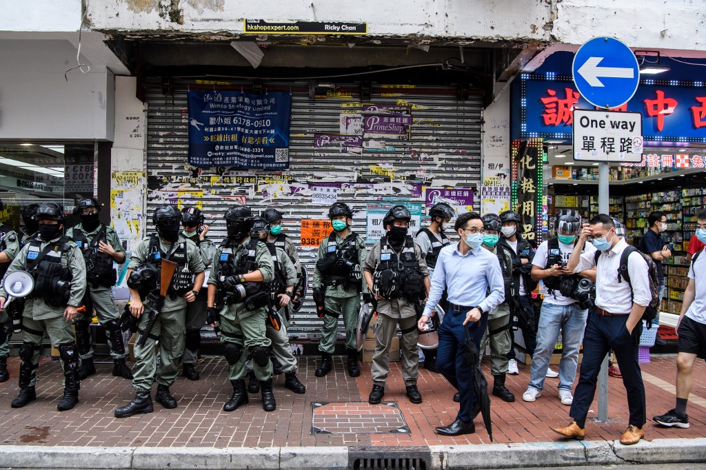 GUARD. Pedestrians walk past a group of riot police standing guard in a front of a shop in the Causeway Bay district of Hong Kong on May 27, 2020. Photo by Anthony Wallace/AFP 