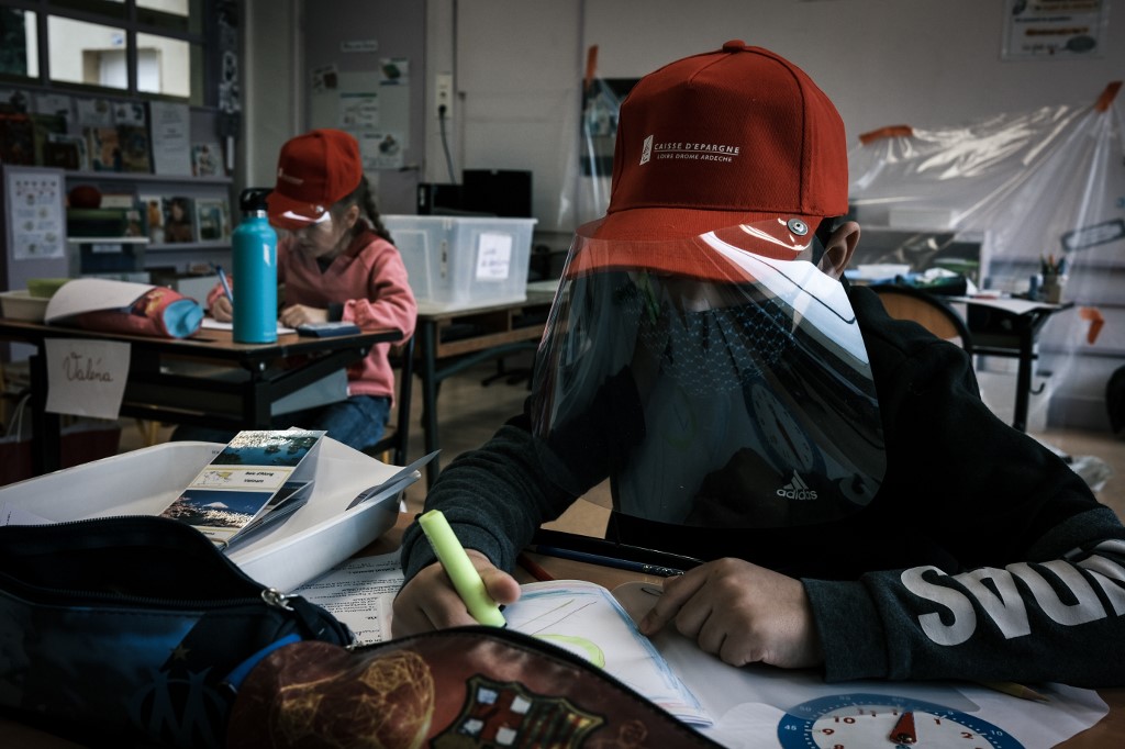 STUDY. Primary school pupils attend a class wearing protective visor caps made by the city council in La Grand-Croix, near Saint-Etienne, central France, on May 12, 2020. Photo by Jean-Philippe Ksiazek/AFP 