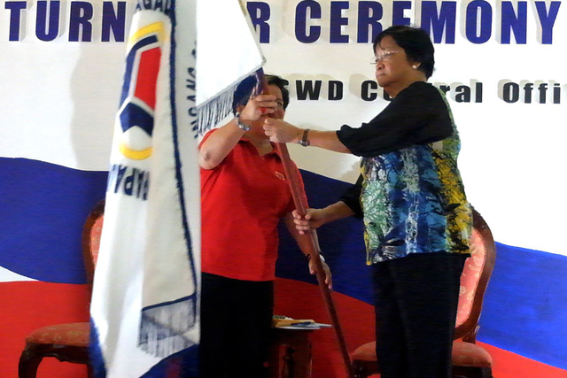 DSWD. Secretary Judy Taguiwalo (right) receives the official flag of the department from outgoing Secretary Corazon Juliano-Soliman at the DSWD Central Office. Photo courtesy of Kodao Productions    