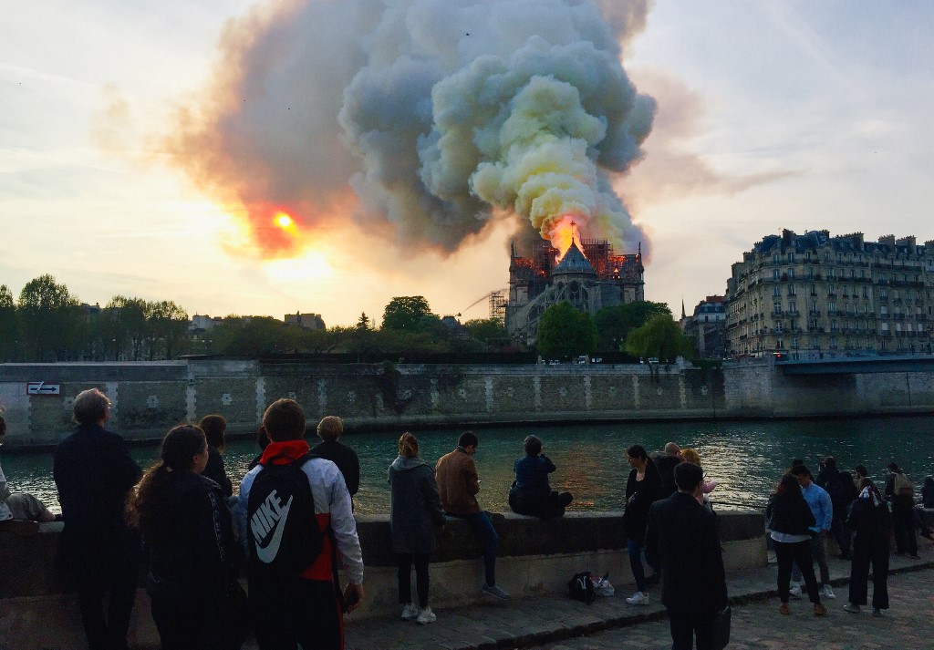 CATHEDRAL FIRE. Bystanders look on as flames and smoke billow from the roof at Notre-Dame Cathedral in Paris on April 15, 2019. Photo by Fouad Maghrane/AFP 