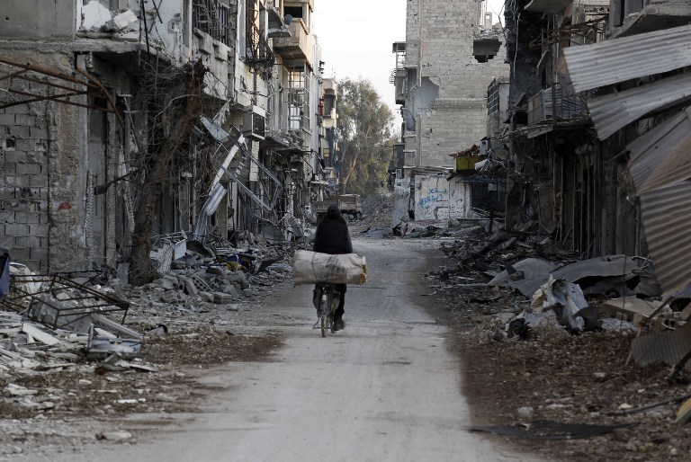 GHOST TOWN. Syrian man rides his bike along a street damaged by shelling in the rebel-held part of Jubar neighborhood, in the Syrian capital Damascus, on February 24, 2016. Abdulmonam Eassa/AFP 