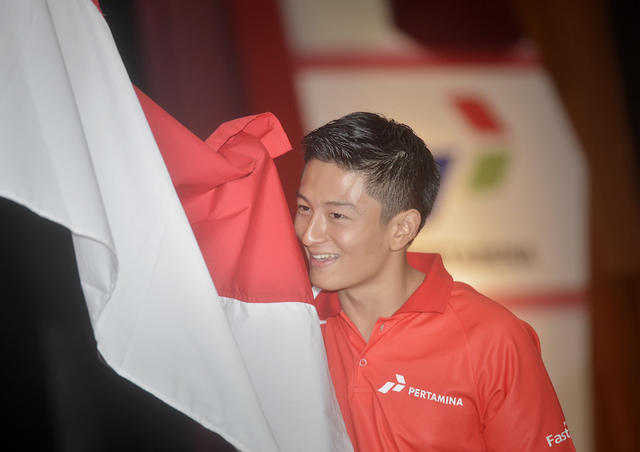 Pembalap Tim Manor Racing Rio Haryanto memegang bendera Merah Putih usai pernyataan dukungan pemerintah dan BUMN untuk berlaga di Formula 1, pada 18 Februari 2016. Foto oleh Yudhi Mahatma/Antara