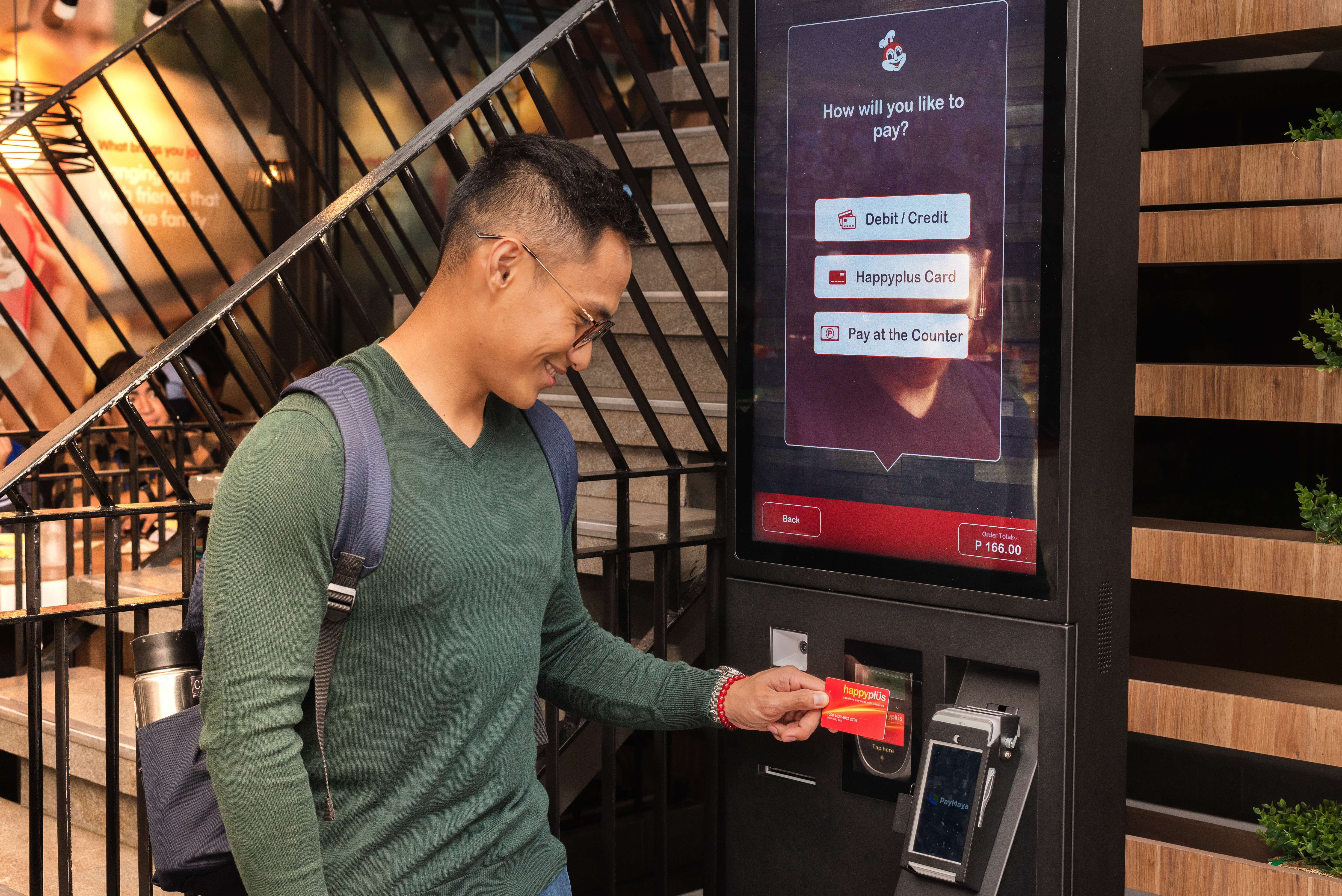 GOING CASHLESS. A customer pays his order at the self-order kiosks using his Happyplüs card at Jollibee BGC Triangle Drive, the fast food chain’s 1000th store in the country. 
