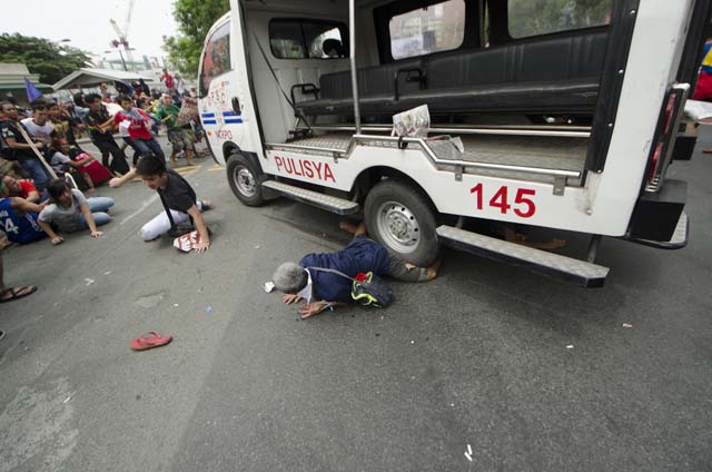 TRAPPED. A protester gets trapped under the wheel of a police van after the vehicle rammed through people holding a rally outside the US embassy. Photo by Rob Reyes  