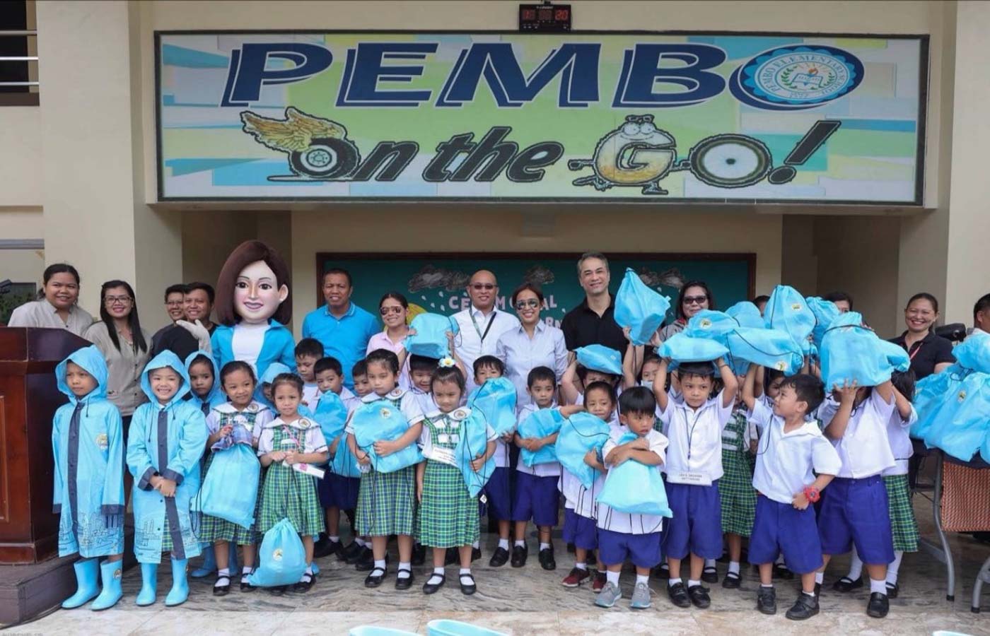 Mayor Abby Binay (center), her husband Makati 2nd District Representative Luis Campos, and Vice Mayor Monique Lagdameo distribute raincoats and rain boats to kindergarten students of Pembo Elementary School. Photo from the Makati City government  