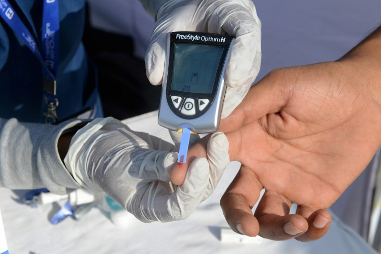 In this photo, an Indian nurse (L) collects a blood sample from a policeman using a glucometer at a free diabetic health check-up camp on World Health Day in Hyderabad on April 7, 2016.  Noah Seelam/AFP 