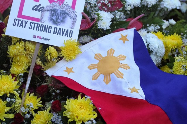 MOURNING. A national flag is placed among flowers as residents offer prayers for bomb blast victims at a night market, during a memorial at the site in Davao City, September 3, 2016. Photo by Stringer/AFP 