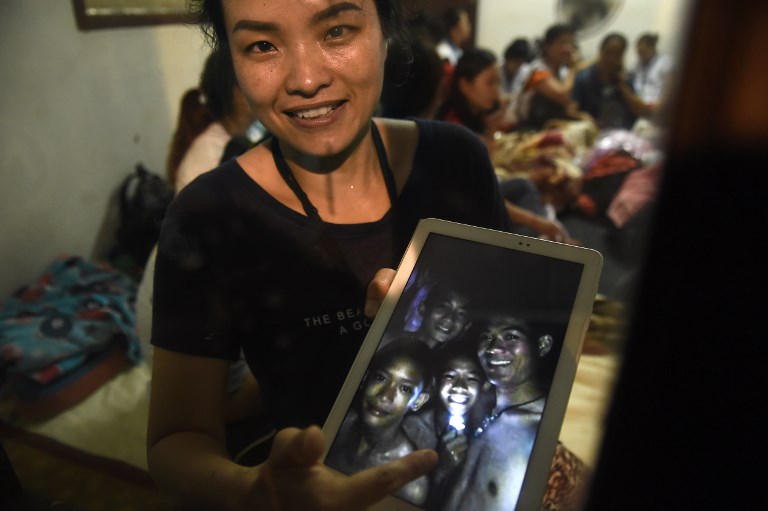 'FOUND SAFE.' A family member shows a picture of 4 of the 12 missing boys near the Tham Luang cave at the Khun Nam Nang Non Forest Park in Mae Sai on July 2, 2018. Photo by Lillian Suwanrumpha/AFP 