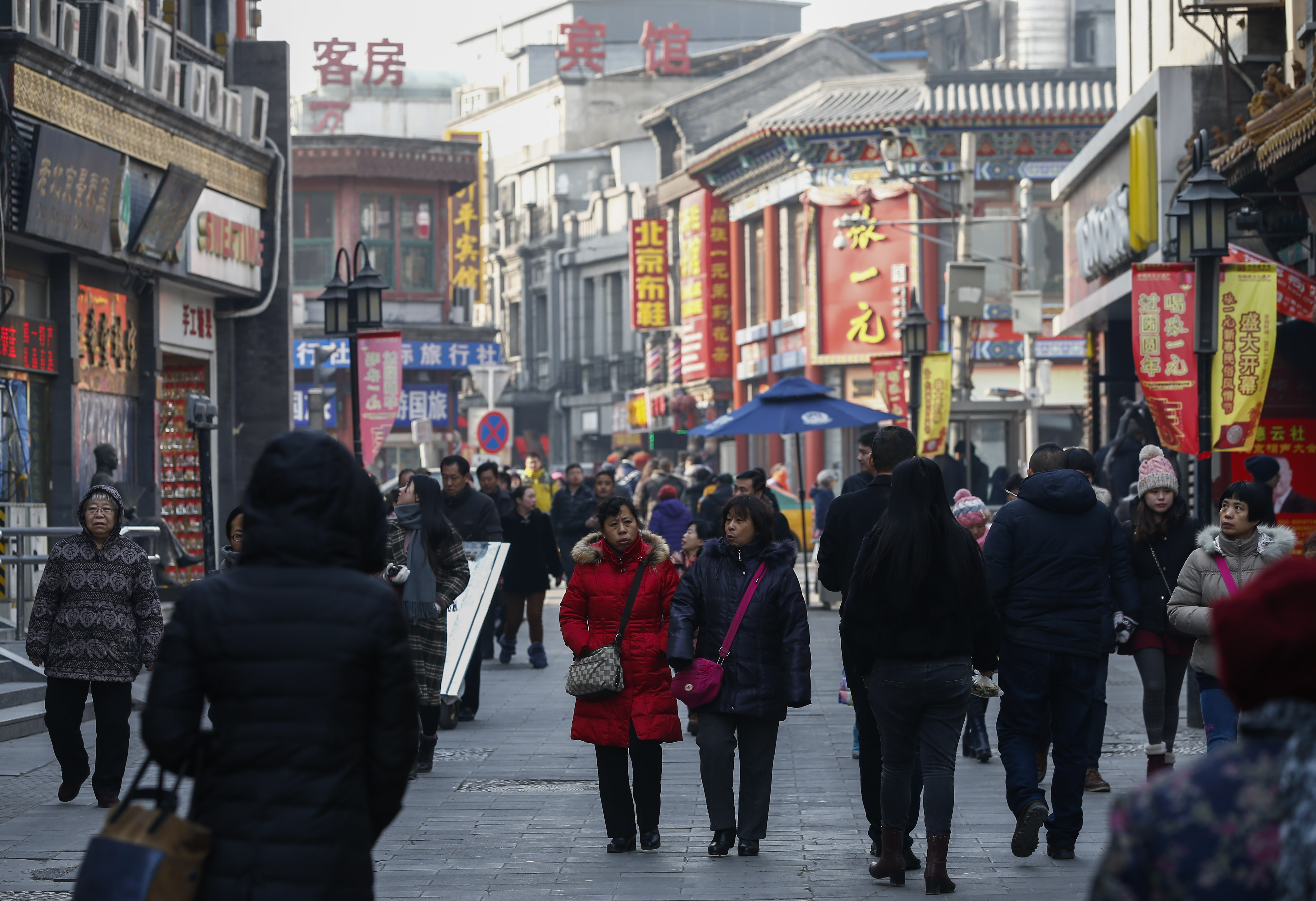 ECONOMIC SLOWDOWN. Citizens walk past commercial establishments at the shopping area of Qianmen district in Beijing, China, January 19, 2016. File photo by Rolex Dela Peña/EPA  