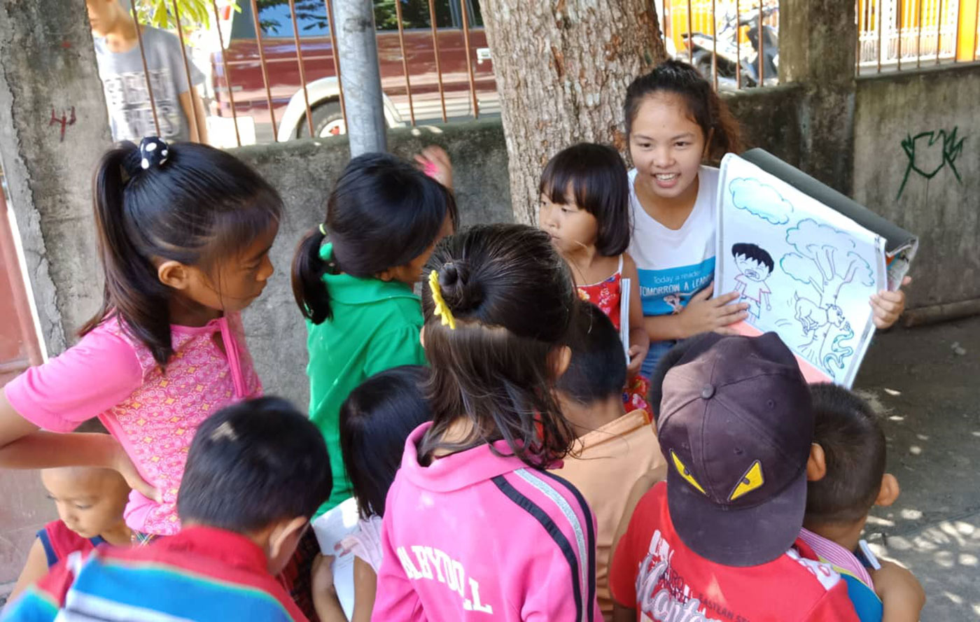 LITERACY ADVOCATE. A young volunteer teacher from San Jose Elementary School in Donsol town, Sorsogon, teaches children to read a book on the street. Photo by Rhaydz B. Barcia/Rappler 