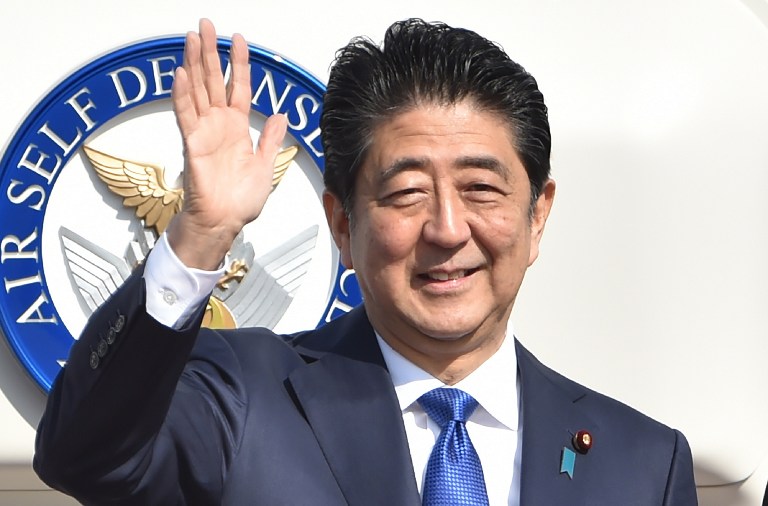 Japan's Prime Minister Shinzo Abe waves to well-wishers prior to boarding a government plane at Tokyo's Haneda on November 17, 2016. Kazuhiro Nogi/AFP 