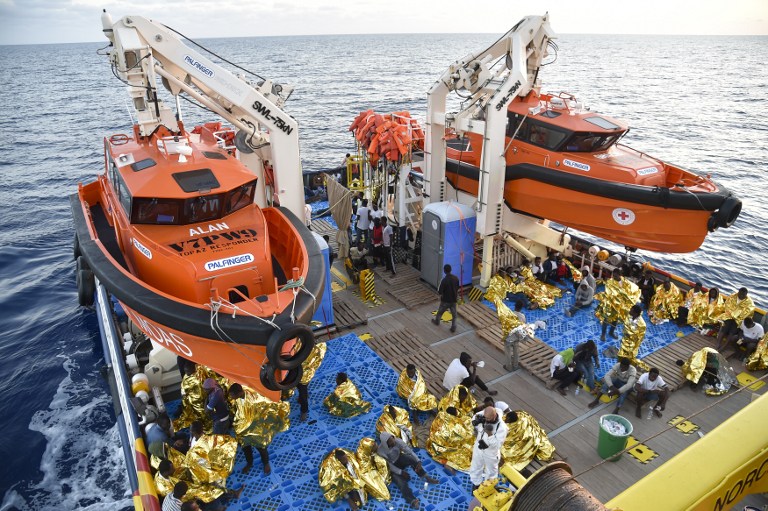 Migrants and refugees wrapped in survival foil blankets rest aboard the Topaz Responder ship run by Maltese NGO Moas and the Italian Red Cross after a rescue operation of migrants and refugees on November 3, 2016, off the Libyan coast in the Mediterranean Sea. Andreas Solaro/AFP 
