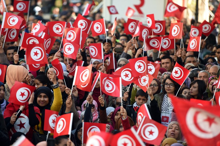 In this file photo, Tunisians wave national flags and shout slogans on January 14, 2016, during a rally on Habib Bourguiba Avenue in Tunis to mark the fifth anniversary of the 2011 revolution. Fethi Belaid/AFP 
