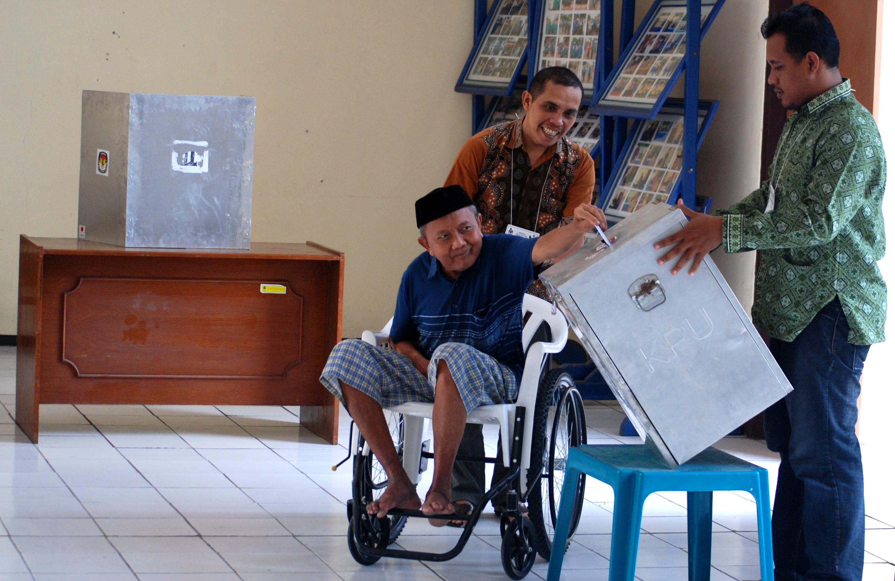 Petugas membantu warga lanjut usia memasukkan surat suara ke dalam kotak di TPS 3 di Panti Jompo Wening Wardoyo, Ungaran Barat, Kabupaten Semarang, Jawa Tengah, dalam Pilkada serentak, 9 Desember 2015. Foto oleh Aditya Pradana Putra/Antara 