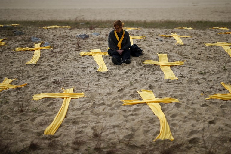 PROTEST ALONG THE BEACH. A woman sits on the beach among yellow clothes shaped as crosses during a protest in support for jailed separatist leaders called by local Republic Defence Committees at Mataro's beach, Barcelona on May 27, 2018. Photo by Pau Barrena/AFP 