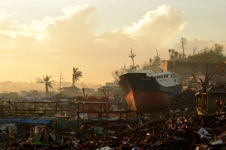 CATASTROPHE. A ship is washed ashore on November 25, 2013, crushing houses in Tacloban, Leyte, after Super Typhoon Yolanda (Haiyan) swept over the central Philippines. File photo by Noel Celis/AFP 