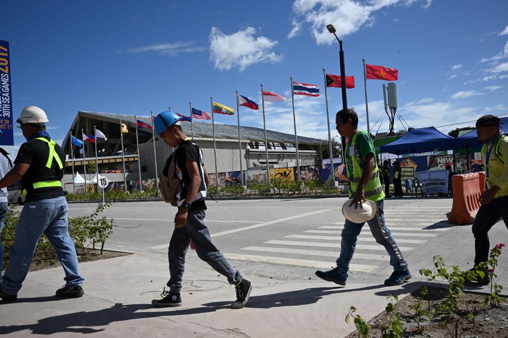 GAME ON. Workers walk past the flags of Southeast Asian countries next to the Aquatic center in New Clark City, in Capas town, Tarlac on November 26, 2019, days ahead of the opening ceremony of SEA Games. Photo by Ted Aljibe/AFP
 