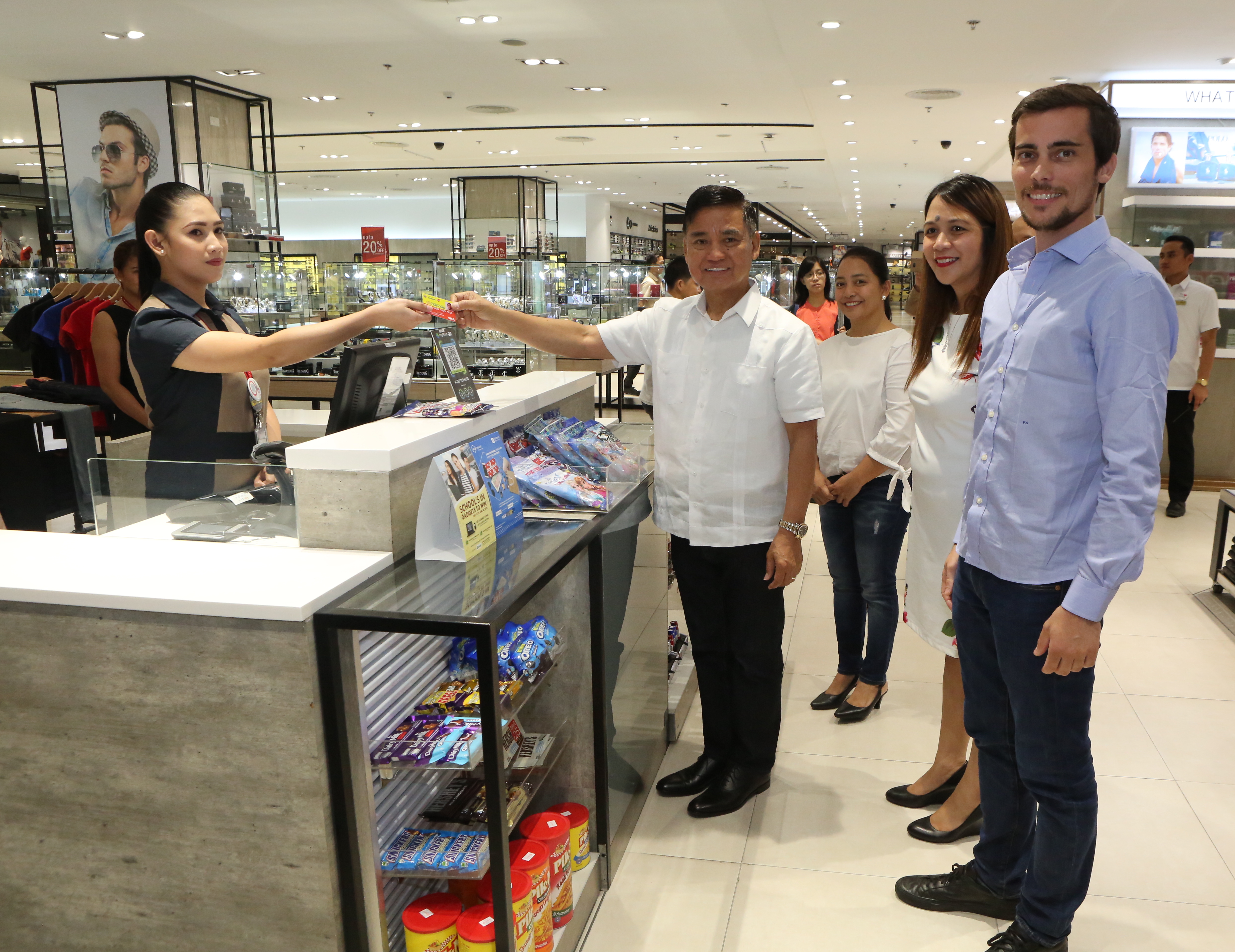 Muntinlupa City Mayor Jaime R. Fresnedi (middle) uses the new Muntinlupa Care Card (MCC) Plus to pay for his purchases at the nearby Robinsons Department Store following the recent launch of the expanded program. Photo from PayMaya 