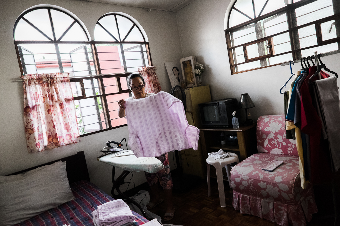 MULTI-TASKING. Anna irons her employer's clothes. She works for 3 different employers and schedules her shifts 6 days a week. She has a son, Buboy, who also works as a helper for the same family.  