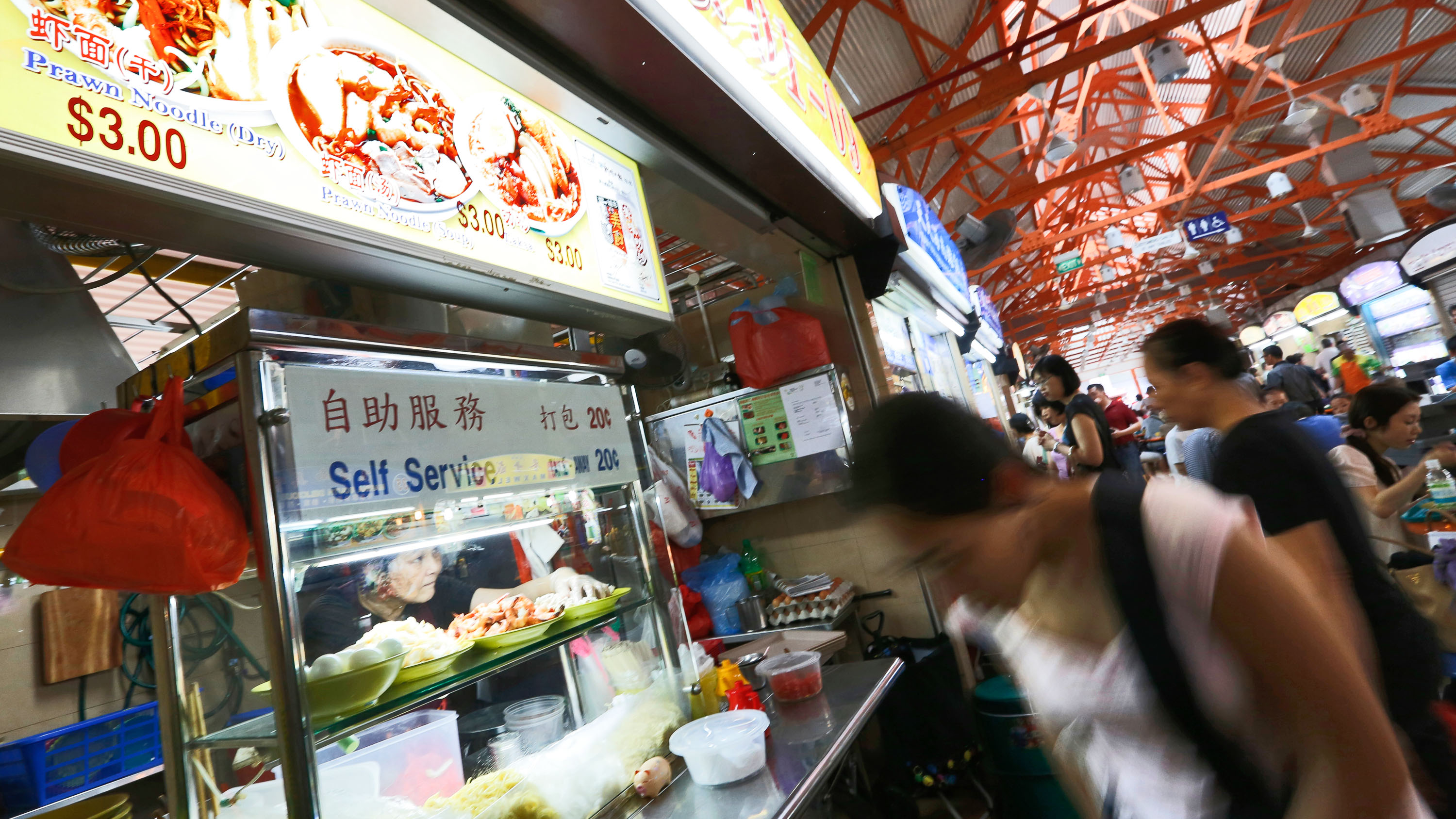 SINGAPOREAN HAWKERS. A noodle stall owner looks out from her food stall as customers walk past in a hawker or food centre in Singapore in 2013. For the first time, Michelin awarded stars to two street food hawkers in Singapore âÂ Hill Street Tai Hwa Pork Noodle and Hong Kong Soya Sauce Chicken Rice & Noodle. File photo by Hwee Young/EPA 