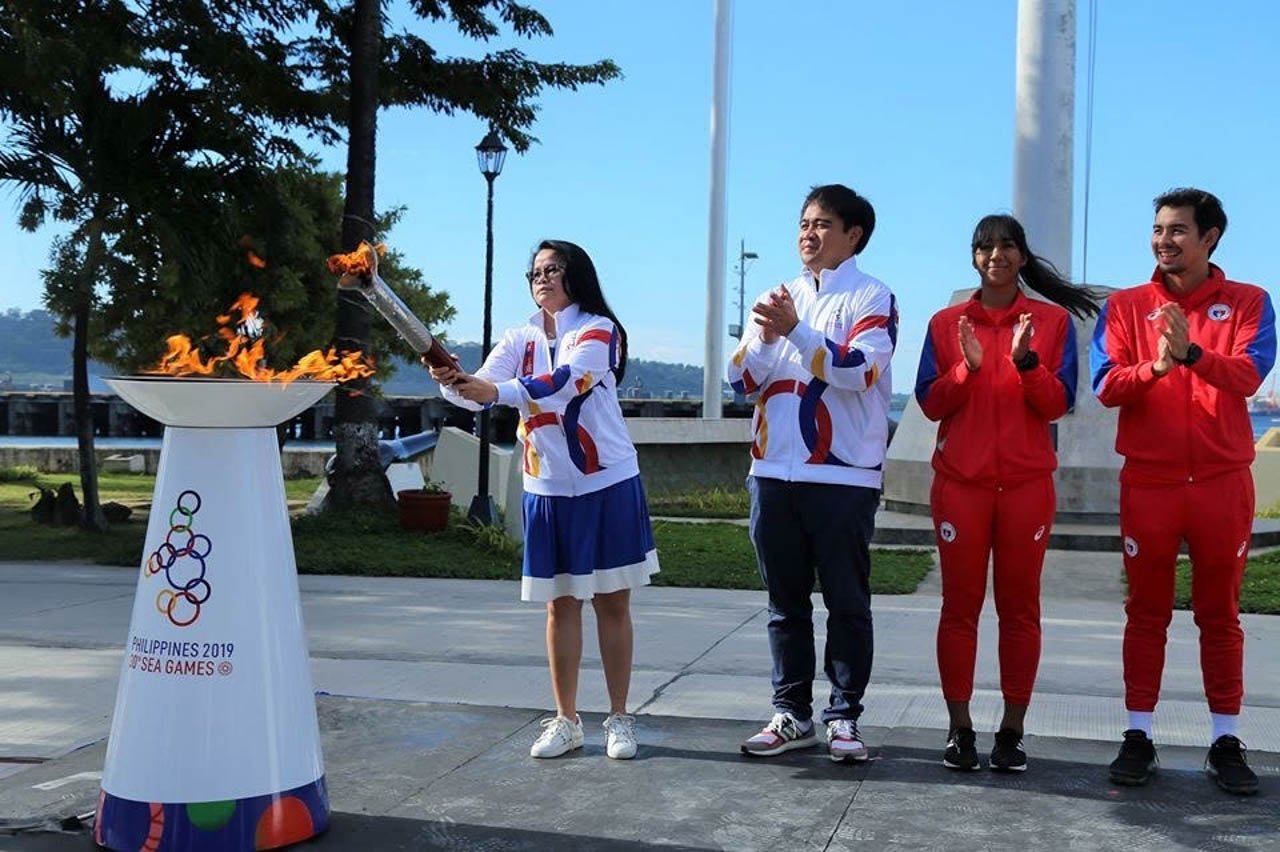 Subic Bay Metropolitan Authority (SBMA) Chairman and Administrator Wilma T. Eisma leads the symbolic lighting of the SEA Games cauldron at the Subic Bay Freeport with Philippine Southeast Asian Games Organizing Committee (PHISGOC) Director for Ceremonies and Cultural Events Mike Aguilar and 2015 SEA Games triathlon gold medal winners Ma. Claire Adorna and Nikko Huelgas. Photo by Randy Datu/Rappler
 