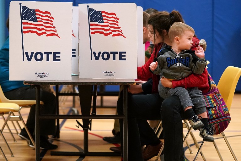 VOTE. Karina Smith holds her 2-year-old son Kyler as she fills out her ballot at the polling place at Washington Mill Elementary School November 7, 2017 in Alexandria, Virginia.  Chip Somodevilla/Getty Images/AFP 