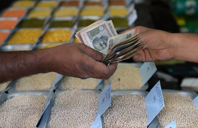 CASH STILL KING. An Indian customer hands over cash to a food grain merchant at a wholesale trading shop in Bangalore on February 28, 2017. Manjunath Kiran/AFP 