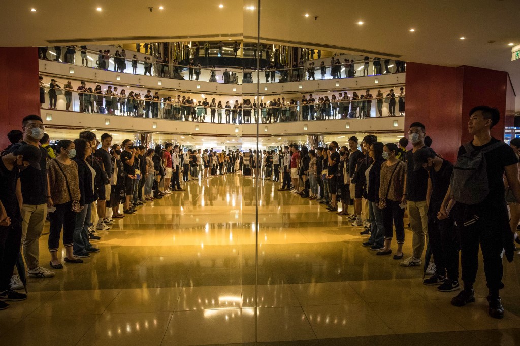 JOINING HANDS. Protesters are reflected in a mirror as they join hands to form a human chain inside the City Plaza mall in the Tai Koo Shing area in Hong Kong on November 3, 2019, after a bloody knife fight wounding 6 people occurred there. Photo by Vivek Prakash/AFP 