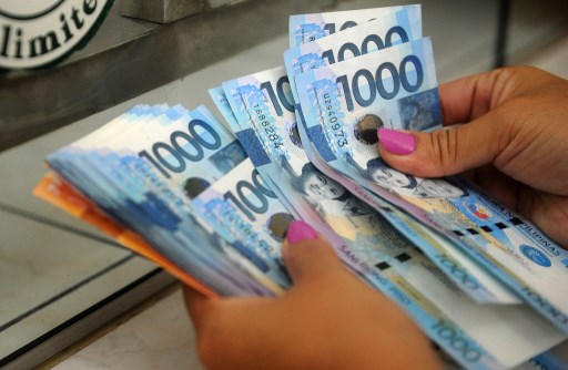 ROBUST. File photo of a customer counting Philippines peso notes after trading his US dollars for Philippine pesos in Manila. Photo by Jay Directo/AFP
 