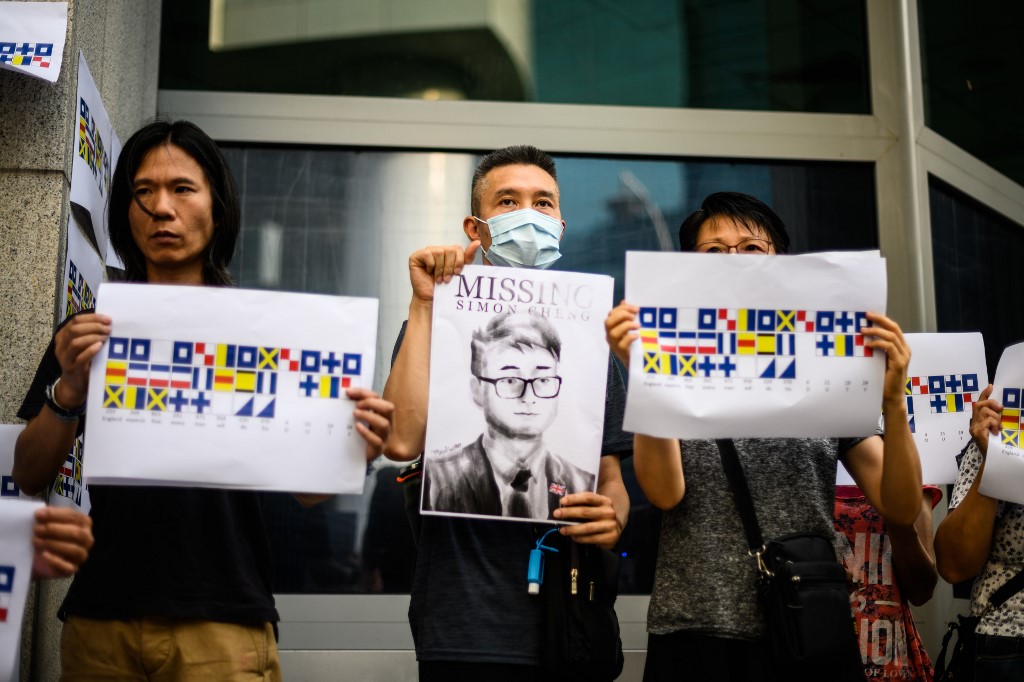 SIMON CHENG. Activists holding placards - one an illustration (C) of Simon Cheng and others carrying a message using International Code of Signals (ICS) flags - gather outside the British Consulate-General building in Hong Kong on August 21, 2019. Photo by Anthony Wallace/AFP 