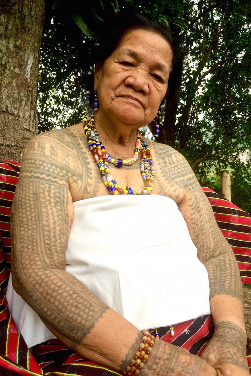 Lasoy upper body portrait: Lasoy sits proudly displaying her tribal tattoos and heirloom beaded necklace 