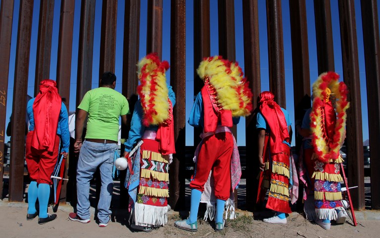 'MATACHINES'. Mexican traditional dancers at the Mexico-US border fence in Ciudad Juarez on November 3, 2018, participate in a mass for Honduran migrants heading via a caravan to the US. Photo by Herika Martinez/AFP 