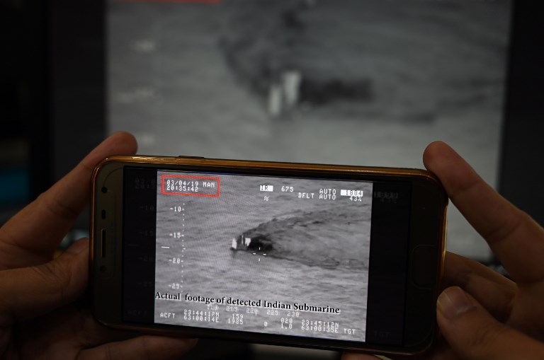 TENSION. A Pakistani journalist watches a video released by Pakistan's Navy that allegedly shows an Indian submarine, on a smartphone in Islamabad on March 5, 2019. Photo by Aamir Qureshi AFP 