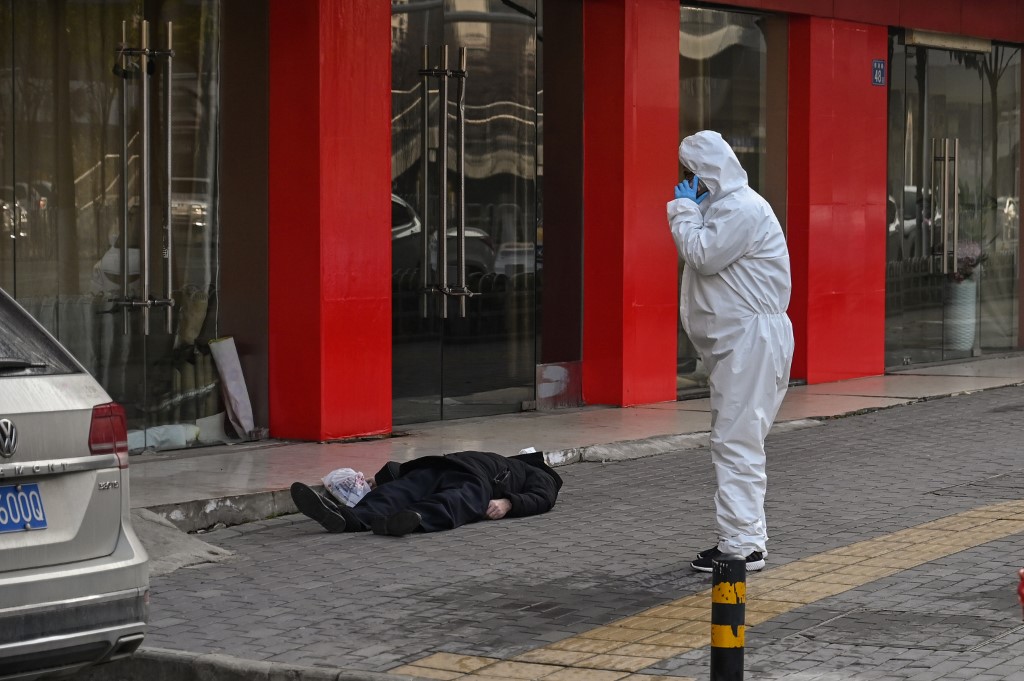CORPSE. This photo taken on January 30, 2020 shows an official in a protective suit checking on an elderly man wearing a face mask who collapsed and died on a street near a hospital in Wuhan. Photo by Hector Retamal/AFP 