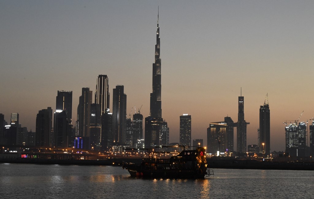 DUBAI SKYLINE. A boat sails at sunset, against the backdrop of Burj Khalifa and high-rise buildings, in the Emirati city of Dubai on May 27, 2020. Photo by Karim Sahib/AFP 