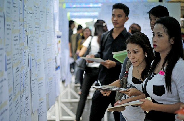 JOB HUNT. Prospective employees check potential employers at a jobs fair. File photo by Ritchie Tongo/EPA    