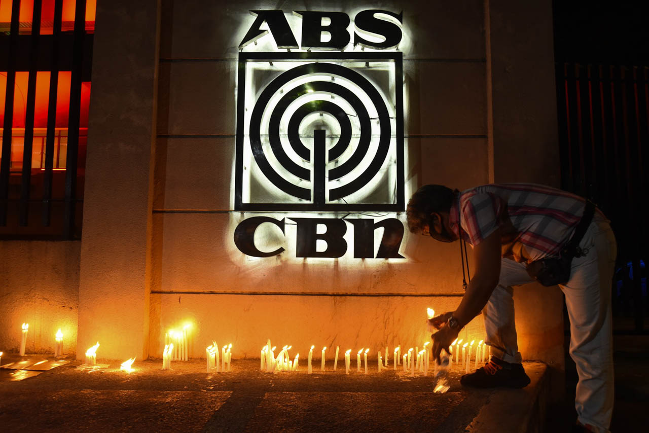 SHUTDOWN. A man lights a candle at the ABS-CBN's facade in Quezon City after its closure on May 5, 2020. File photo by Angie de Silva/Rappler 