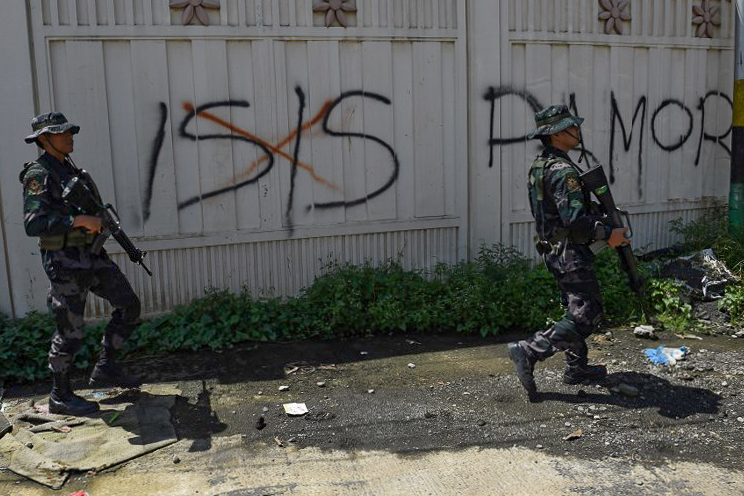 ISIS SCOURGE. Soldiers walk past Islamic State graffiti in Marawi City on May 31, 2017. Photo by Ted Aljibe/AFP 