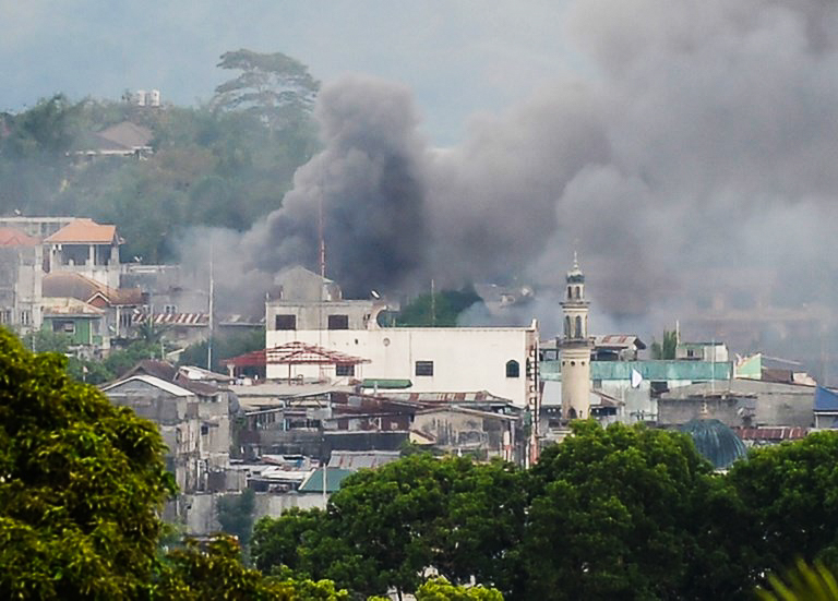 CHAOS, DESTRUCTION. In an early photo of the Marawi crisis, smoke rises near a public market after military helicopters fire rockets on the positions of Muslim extremists. File photo by Ted Aljibe/AFP  
