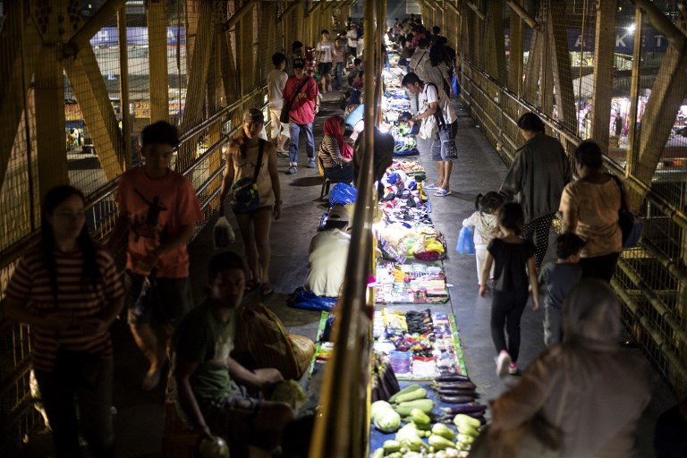 FILIPINO CONSUMERS. This photo taken on April 11, 2018, shows vendors and passers-by along an overpass in Manila. File photo by Noel Celis/AFP 