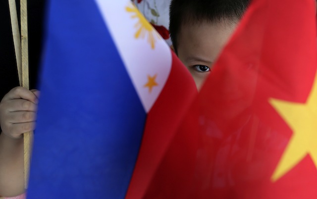 A Vietnamese child peers from Vietnam and Philippines flags while waiting for the arrival of Vietnam Prime Minister Nguyen Tan Dung at Villamor Airbase in Pasay City, Philippines, 21 May 2014. Dennis M. Sabangan/EPA 