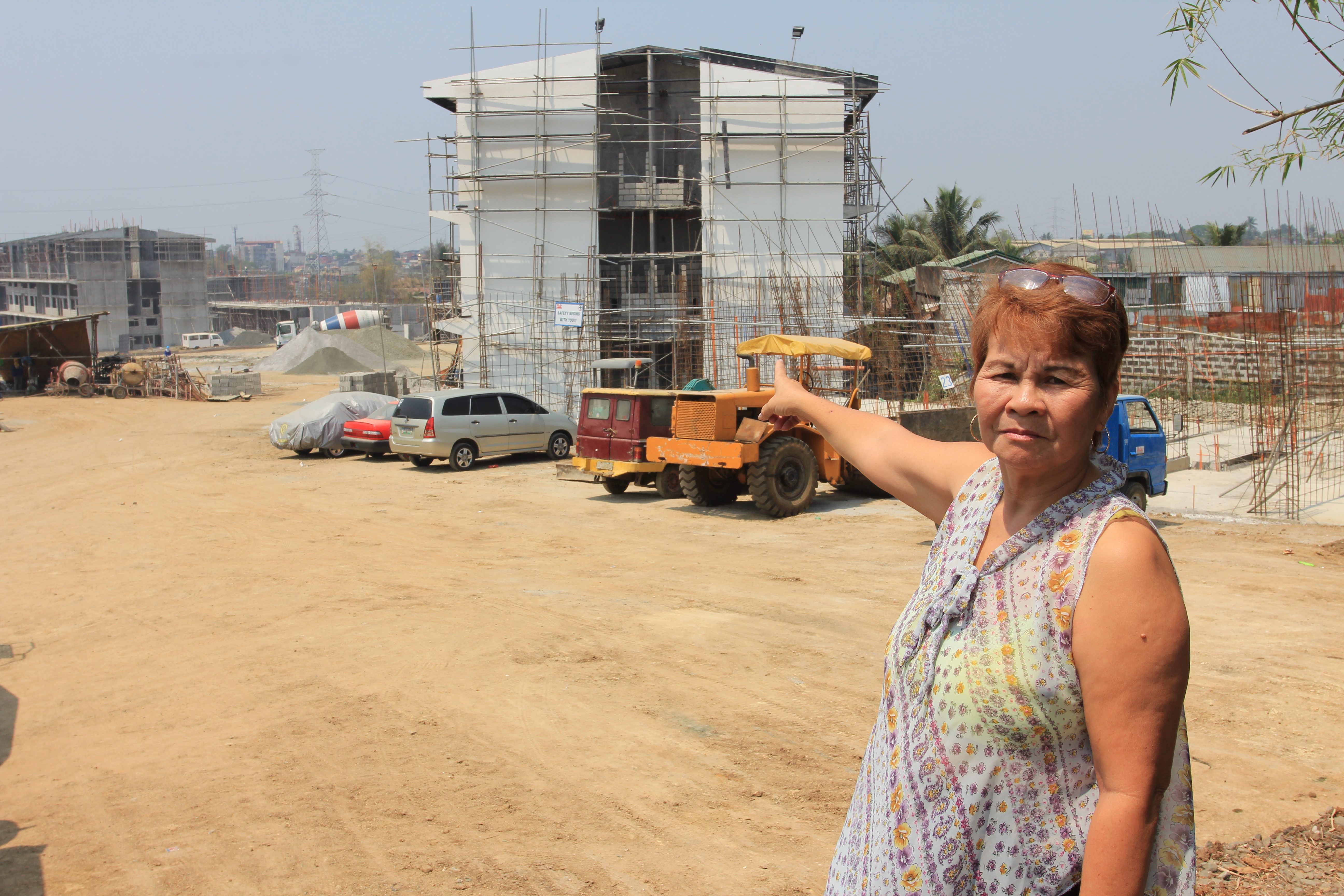 DECENT HOUSING. Former OFW Enriqueta Catayong points to the housing project that will provide decent, secure homes for thousands of relocated informal settlers. All photos by Gerard P. Garcia 