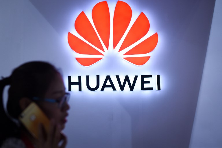 HUAWEI. In this file photo taken on July 8, 2018 a woman uses her mobile phone in front of a Huawei logo at Beijing International Consumer Electronics Expo in Beijing.Photo by Wang Zhao/AFP 