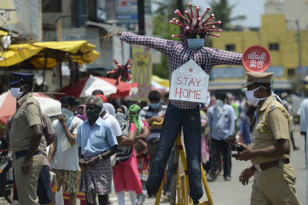'STAY HOME.' People stand in line beside a COVID-19 awareness scarecrow placed at a market in Chennai, India, on April 11, 2020. Photo by Arun Sankar/AFP 