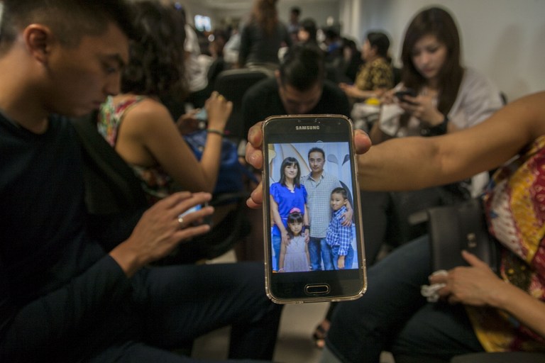 PENUMPANG. Keluarga menunjukkan foto penumpang AirAsia QZ8501 di ponselnya di Bandara Juanda, Surabaya, 28 Desember, 2014. Foto oleh Juni Kriswanto/AFP  