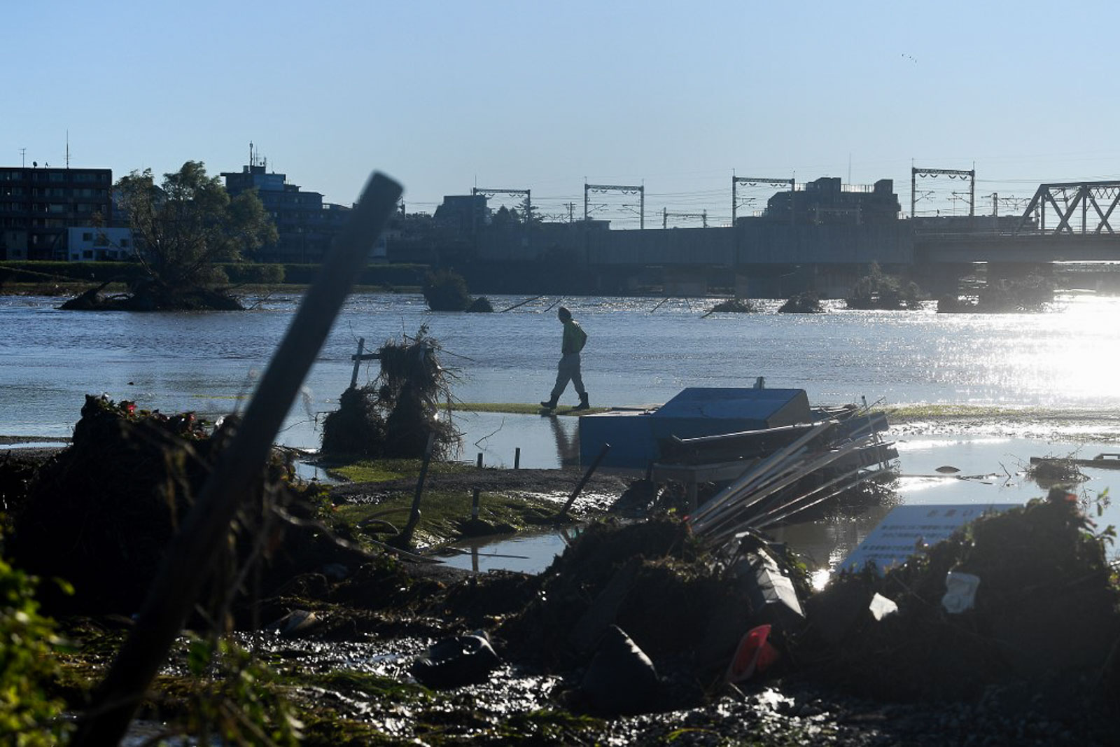 A man walks past debris swept downstream from an overflowing Tamagawa river in the aftermath of Typhoon Hagibis, in Kawasaki on October 13, 2019. Photo by Franck Fife/AFP 