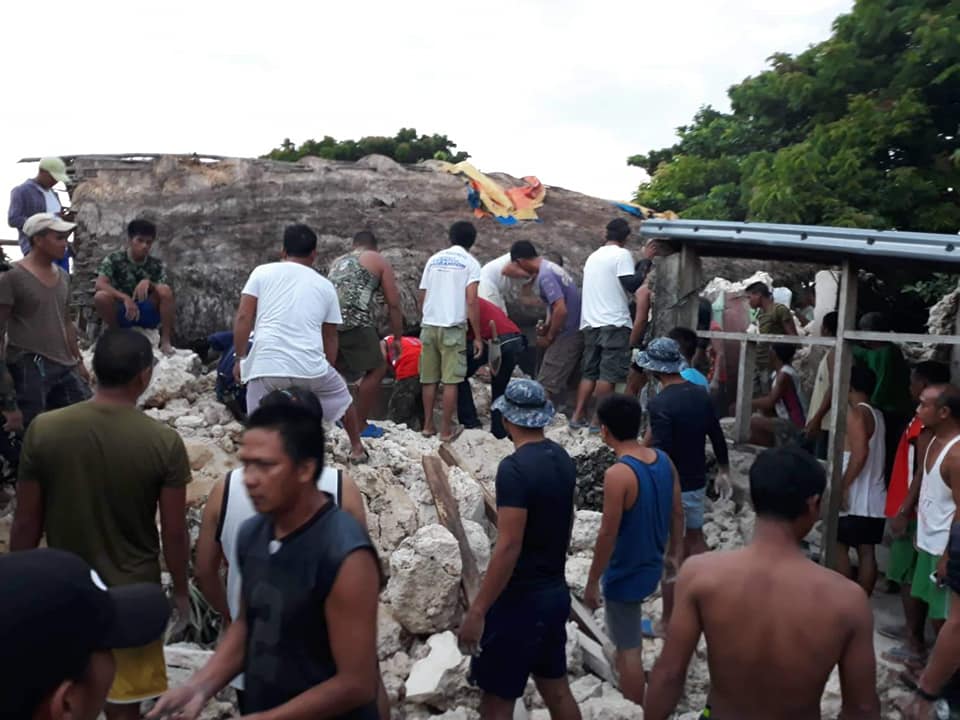 RUBBLE. Itbayat residents gather around a quake-wrecked house where a lifelfess man was pulled out. Photo from PIA Region 2 