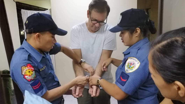 ARRESTED. Police handcuff Lorenzo Marchesi at the holding facility of the Bureau of Immigration in Davao City. Photo from International Justice Mission 
